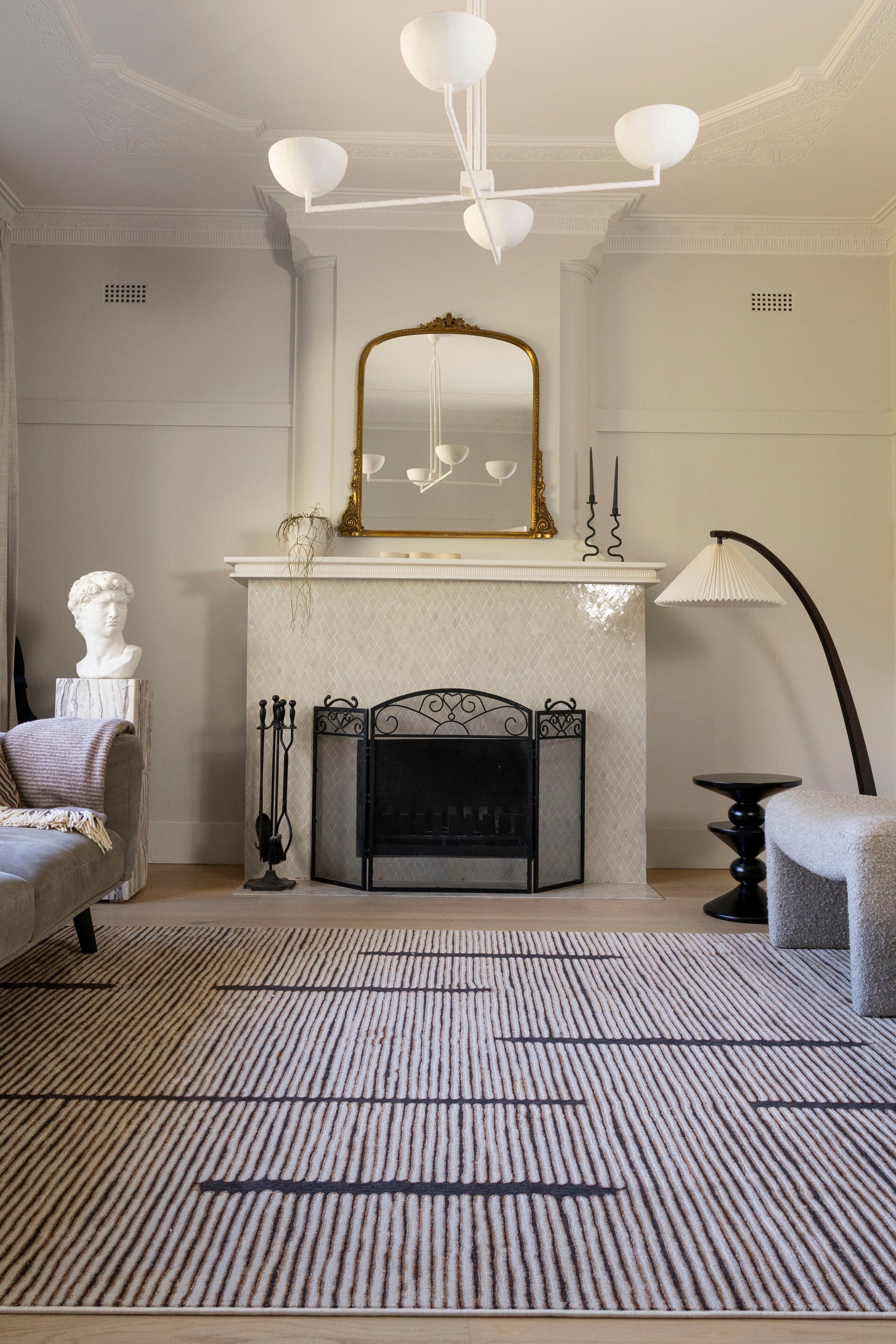 Living room with fireplace, mirror, and decorative items and Midnight Suede Abstract Rug by Four Corners Rugs