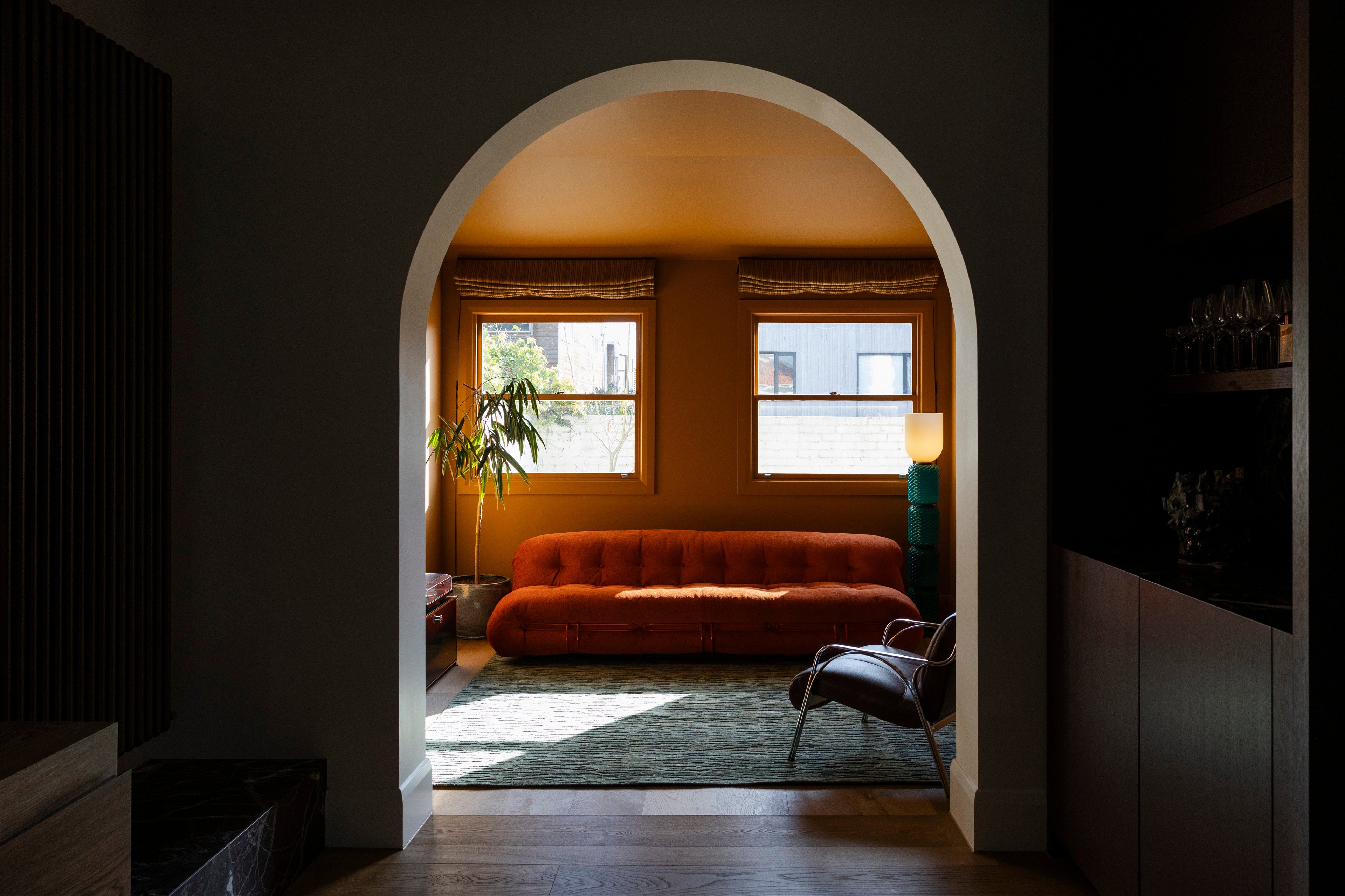 Archway leading into a room with an orange sofa, a lamp and Oceana Forrest Green by Four Corners Rugs