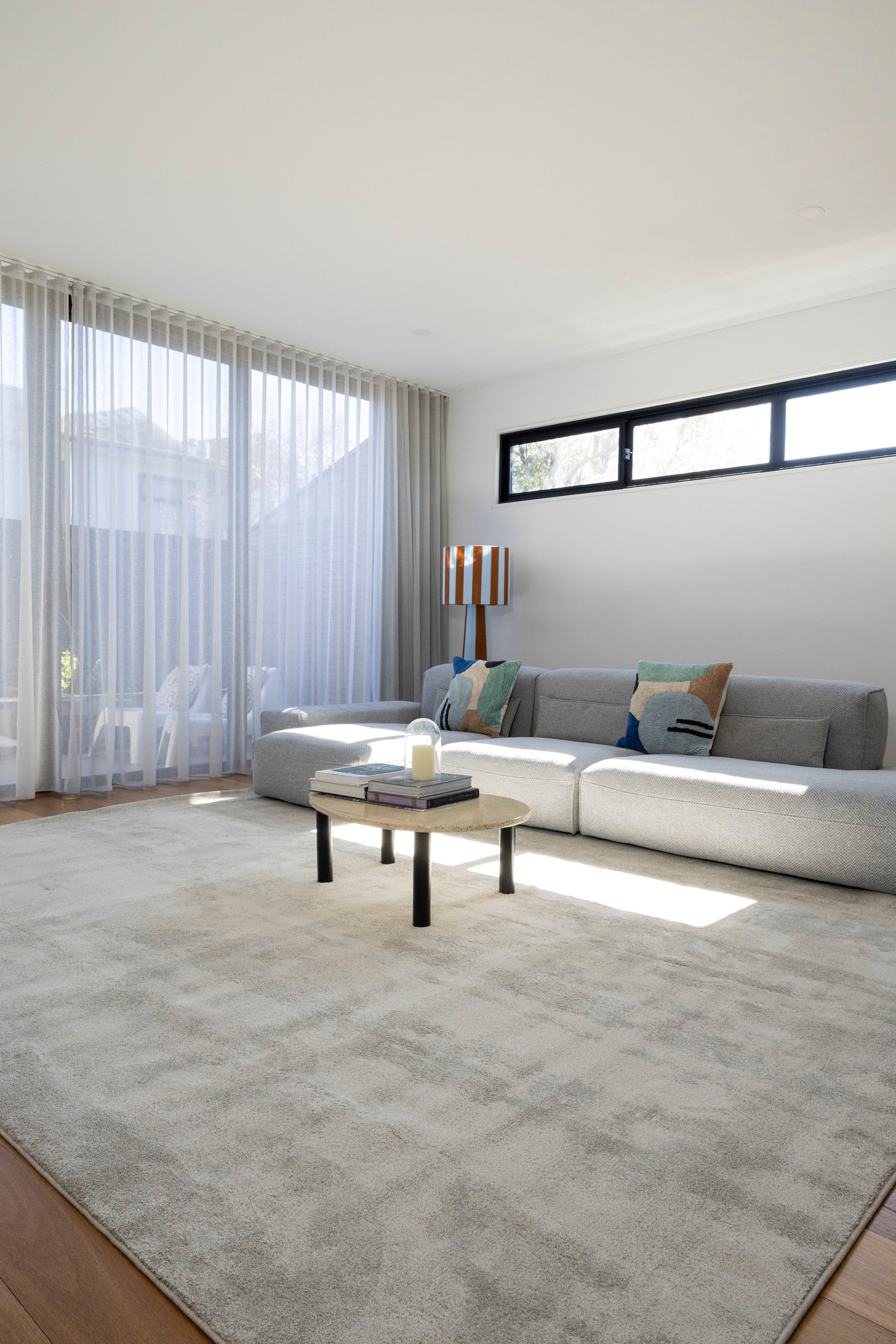 Modern living room with a grey sofa, coffee table, and large windows and Plush Light Grey Rug by Four Corners Rugs