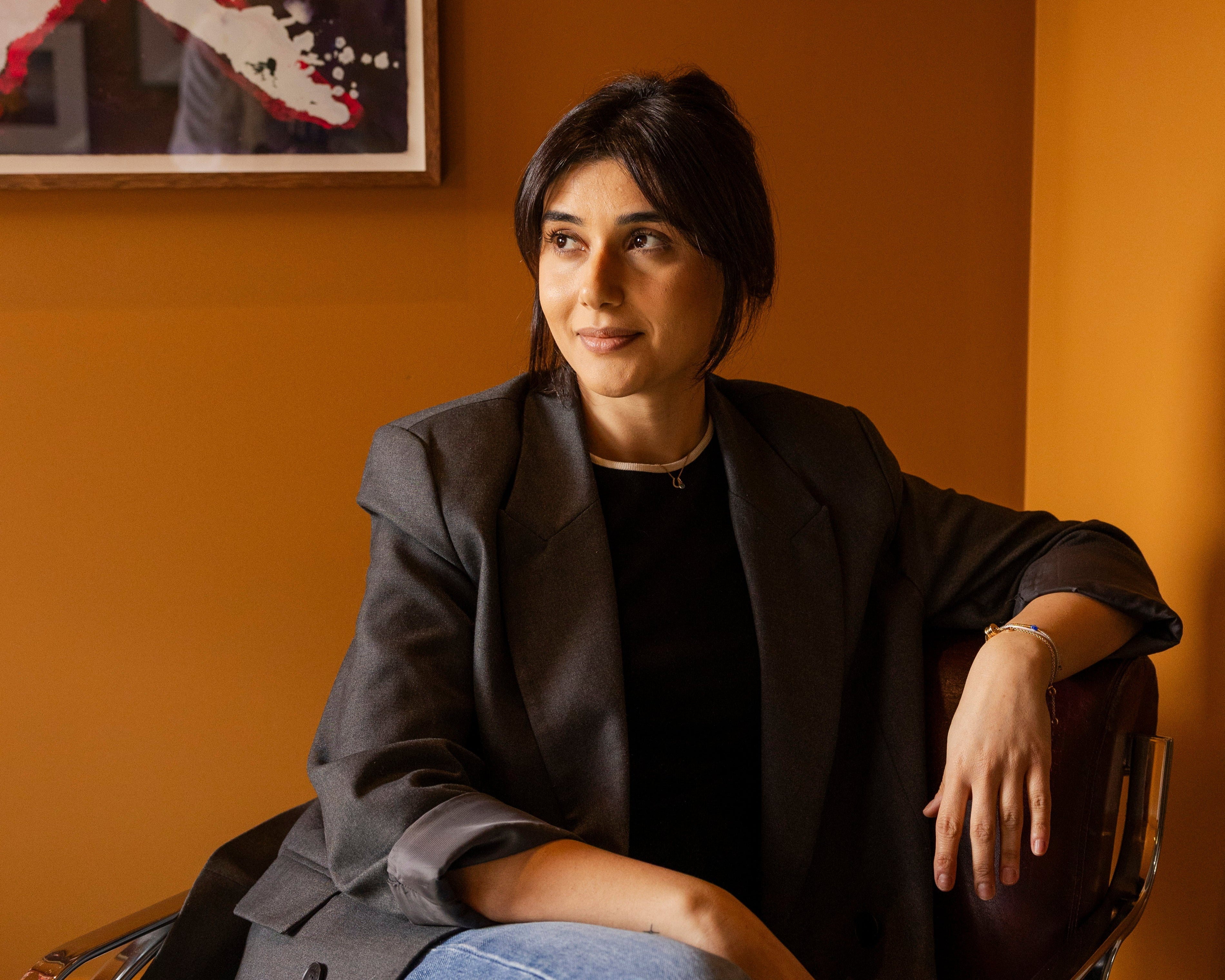 Talla sitting in a chair against an orange wall with a framed picture for rug consults