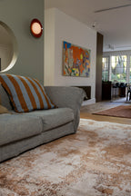 Living room with grey sofa, striped pillow, and Blush Shadow Pink and Rust Rug By Four Corners Rugs
