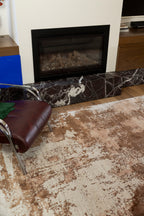 Living room with a fireplace, brown chair, and Blush Shadow Pink and Rust Rug By Four Corners Rugs