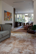 Living room with gray sofa, brown armchair, a painting on the wall and Blush Shadow Pink and Rust Rug By Four Corners Rugs