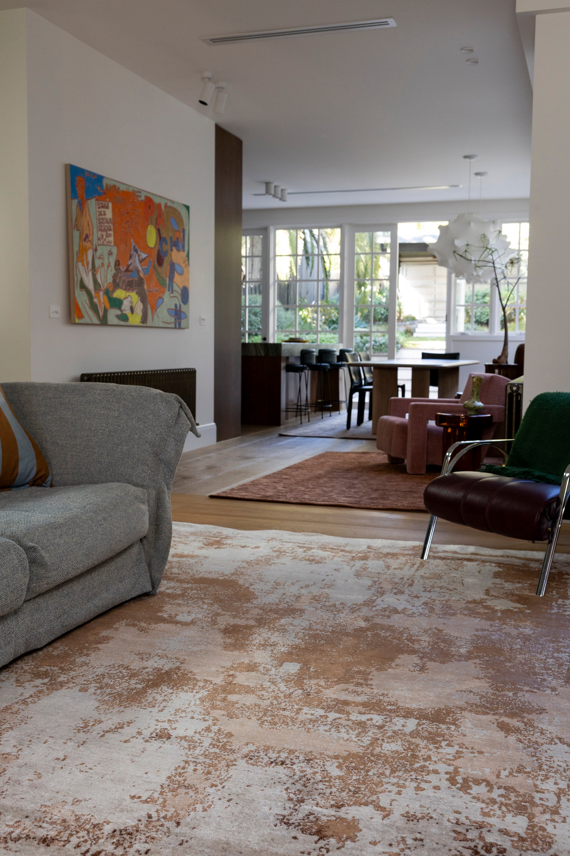 Living room with gray sofa, brown armchair, a painting on the wall and Blush Shadow Pink and Rust Rug By Four Corners Rugs
