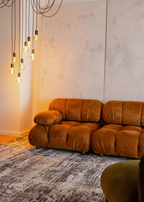 Brown sofa in a room with pendant lights and a textured wall featuring Charcoal Eclipse Rug by Four Corners Rugs