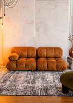 Orange sofa in a room with Charcoal Eclipse Rug by Four Corners Rugs and decorative elements.
