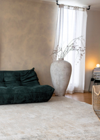 Living room with a dark green sofa, large white vase, light-coloured wall and Christian Grey II Rug by Four Corners Rugs