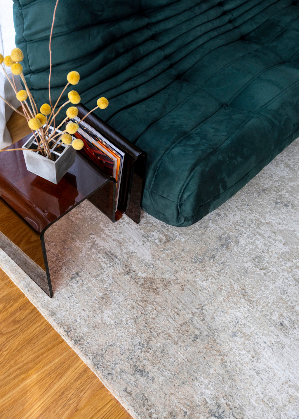 Green futon sofa with a small table and decorative items on Christian Grey II Rug by Four Corners Rugs