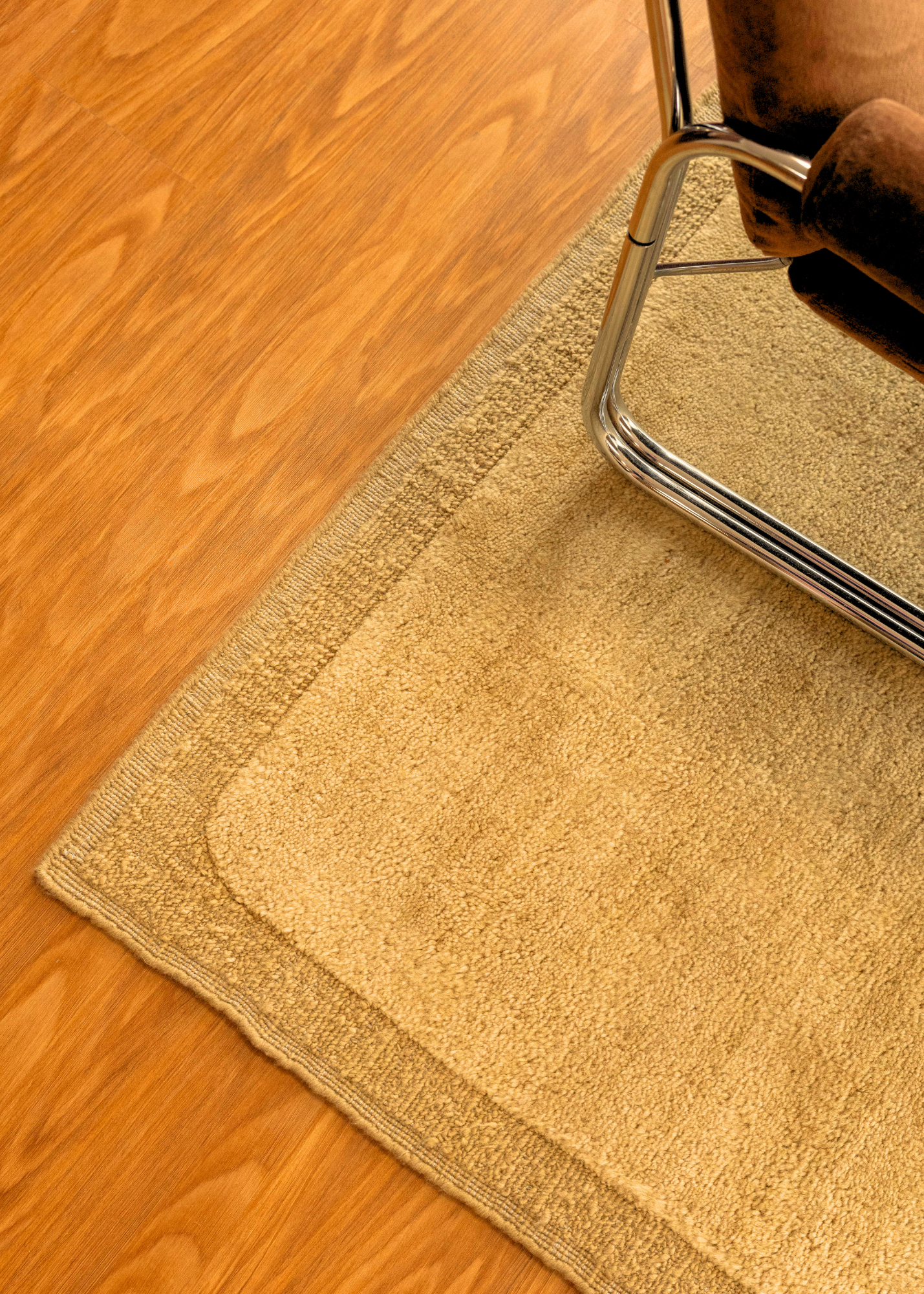 Double Border Mustard Wool Rug by Four Corners Rugs close up with corner of retro chair