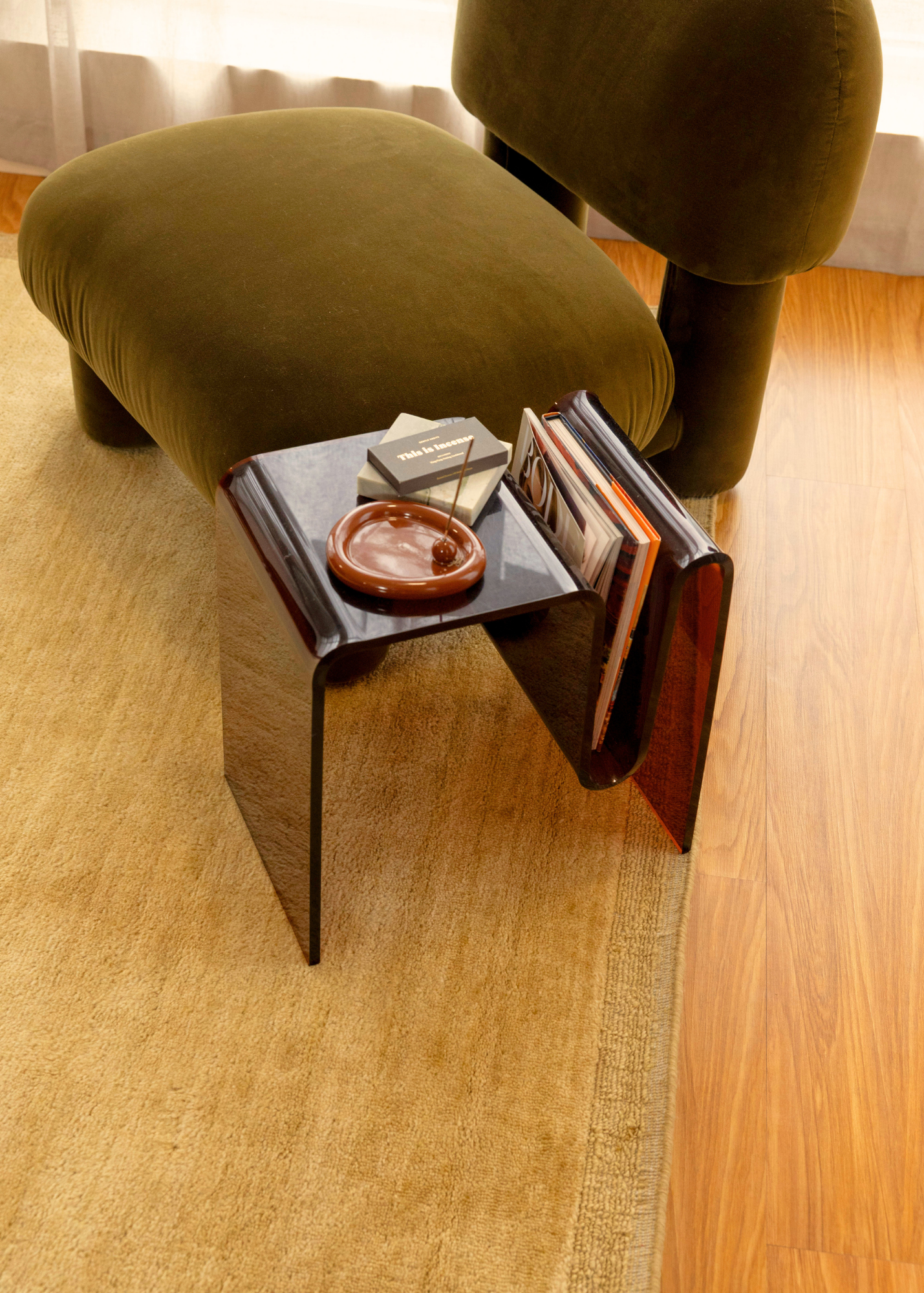 Green chair with a small table holding books and a bowl on a wooden floor featuring Double Border Mustard Wool Rug by Four Corners Rugs