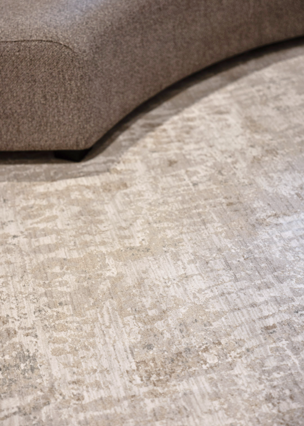 Close-up of Fossil Beige and Grey Rug - Product Pic by Four Corners Rugs with a brown sofa corner.