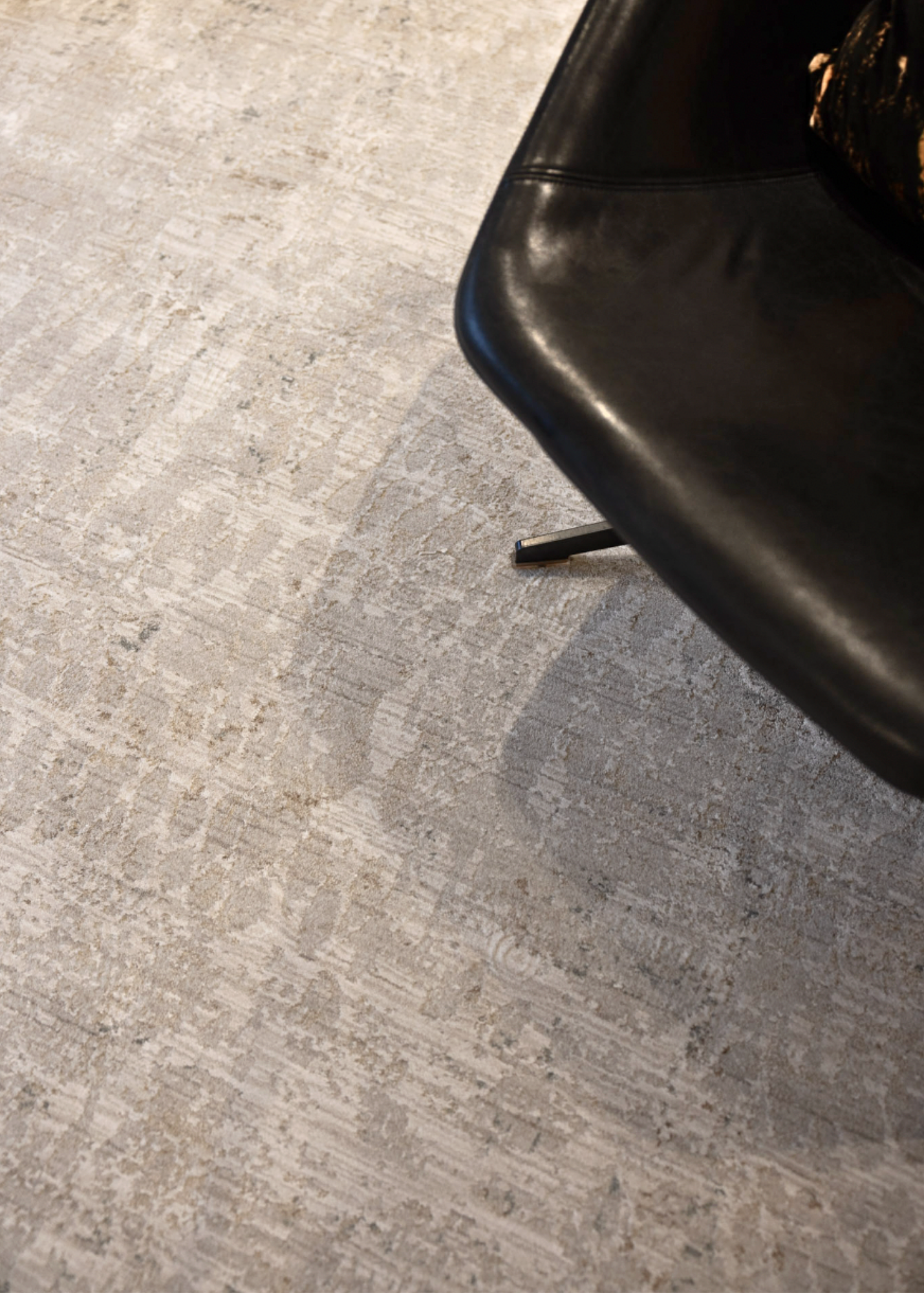 Close-up of a black chair leg Fossil Beige and Grey Rug by Four Corners Rugs