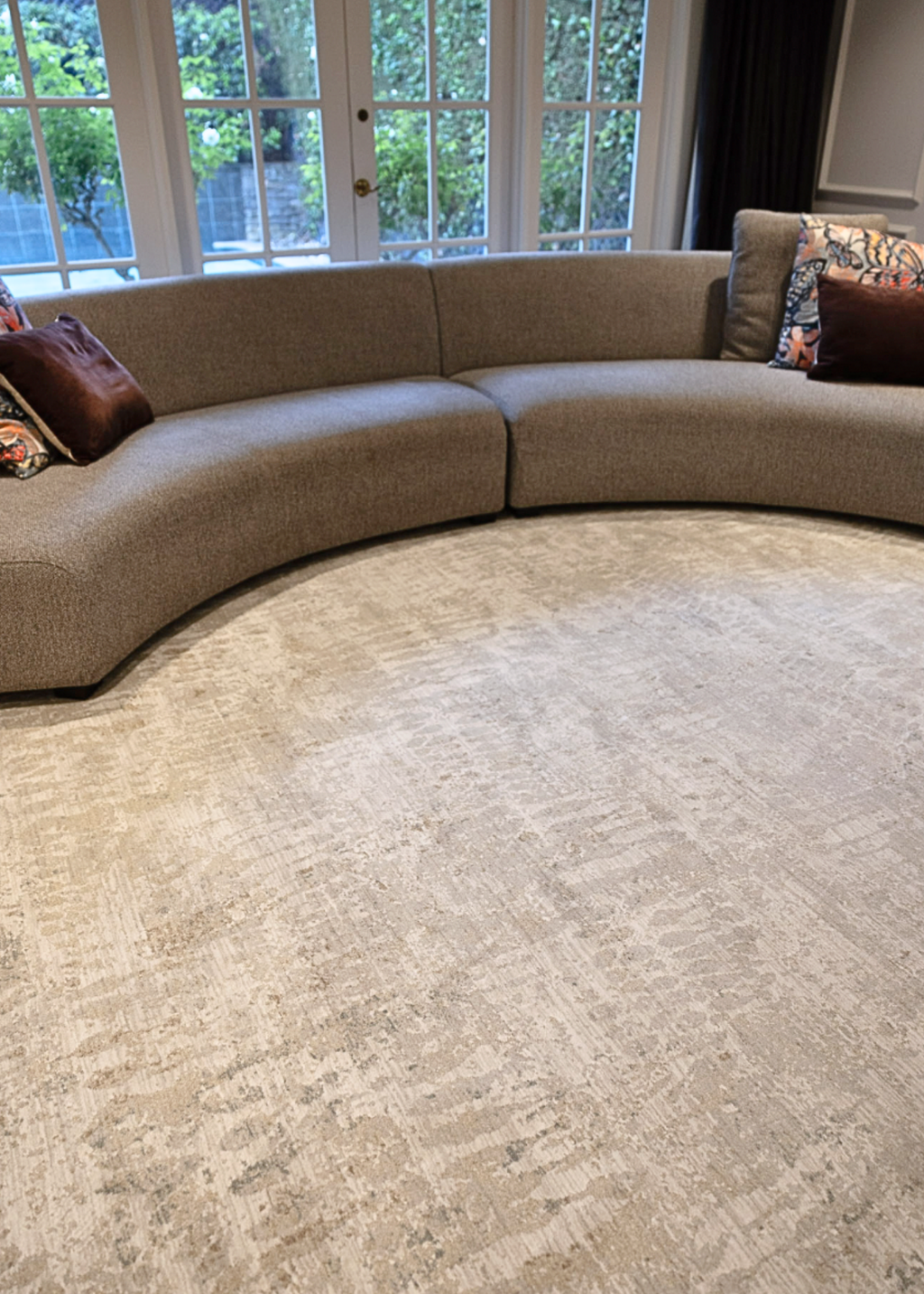 Curved sofa in a living room with Fossil Beige and Grey Rug by Four Corners Rugs