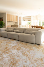 Large beige sectional sofa in a living room with Golden Dusk Abstract Rug by Four Corners Rugs