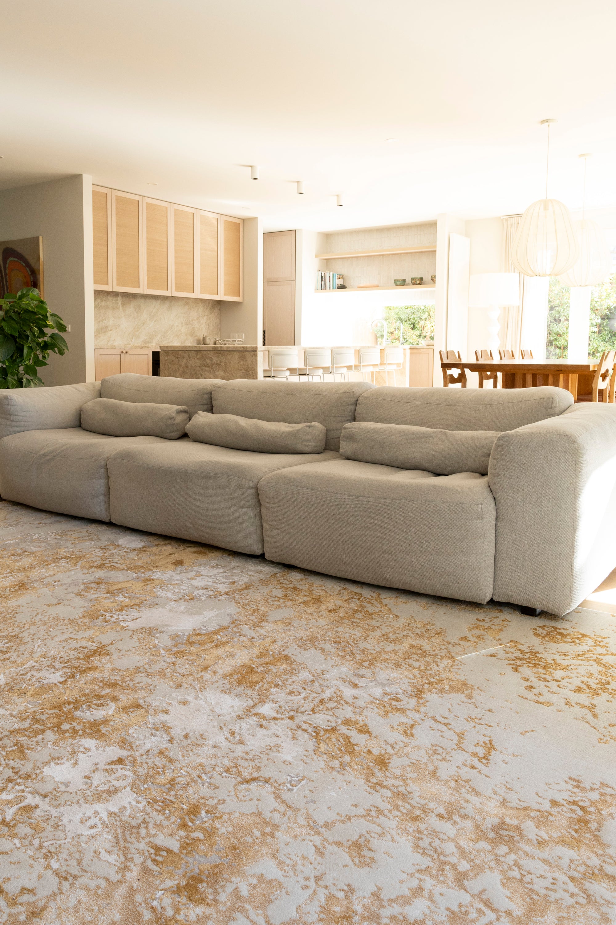 Large beige sectional sofa in a living room with Golden Dusk Abstract Rug by Four Corners Rugs