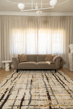 Grey sofa with patterned pillows on Moonlit Bloom Abstract Rug by Four Corners Rugs