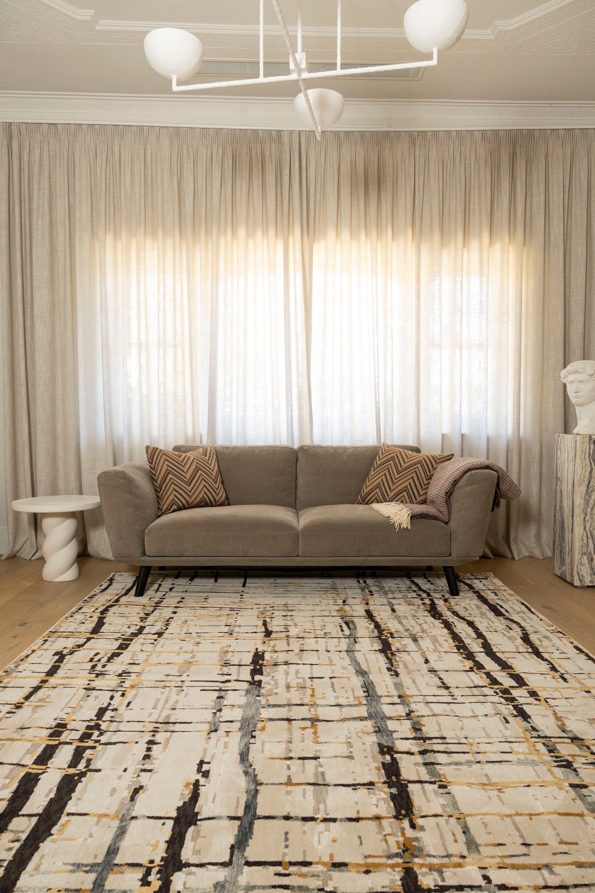 Grey sofa with patterned pillows on Moonlit Bloom Abstract Rug by Four Corners Rugs