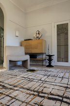 Living room with Moonlit Bloom Abstract Rug by Four Corners Rugs, chair, and wooden cabinet.