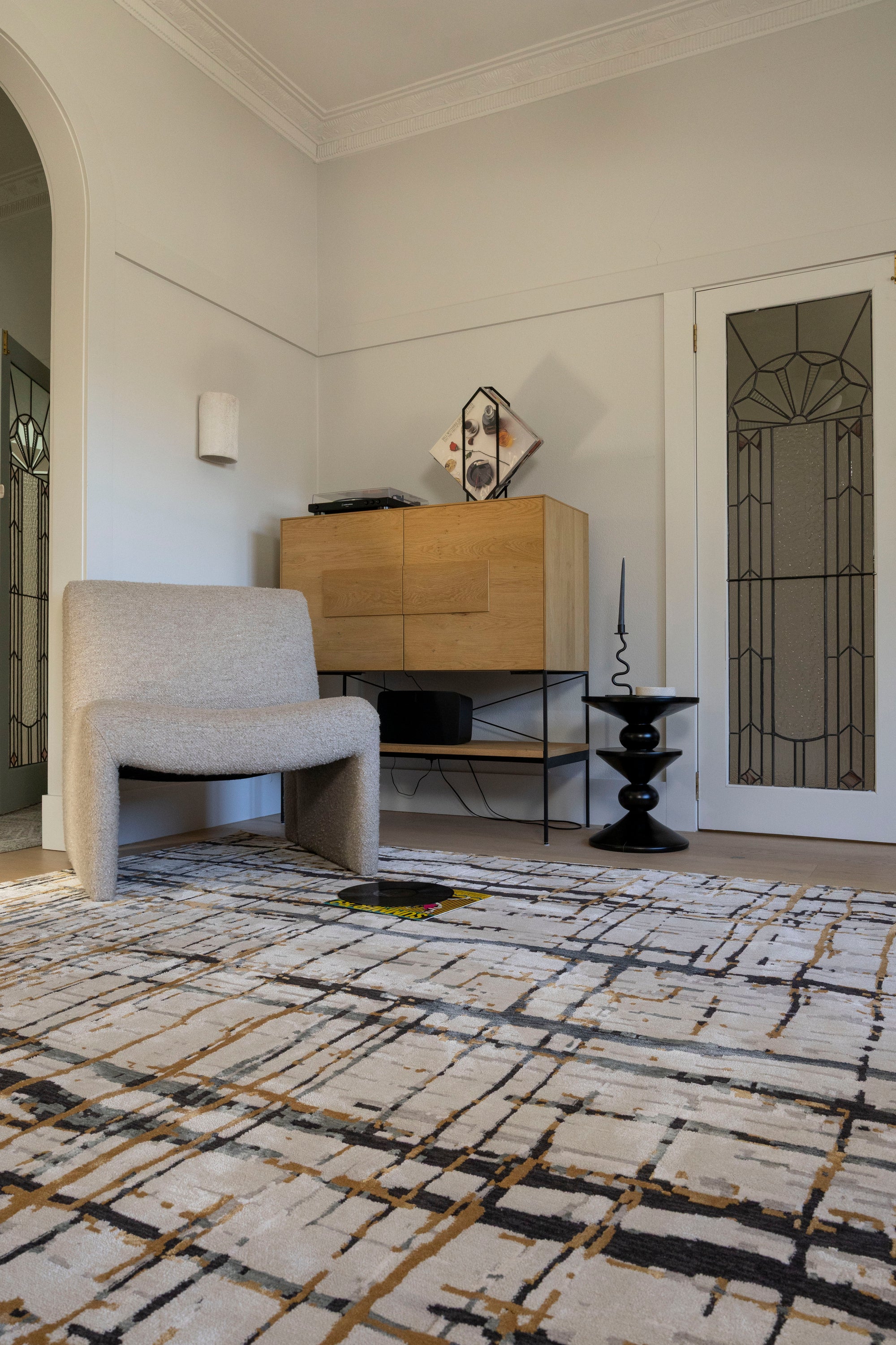Living room with Moonlit Bloom Abstract Rug by Four Corners Rugs, chair, and wooden cabinet.