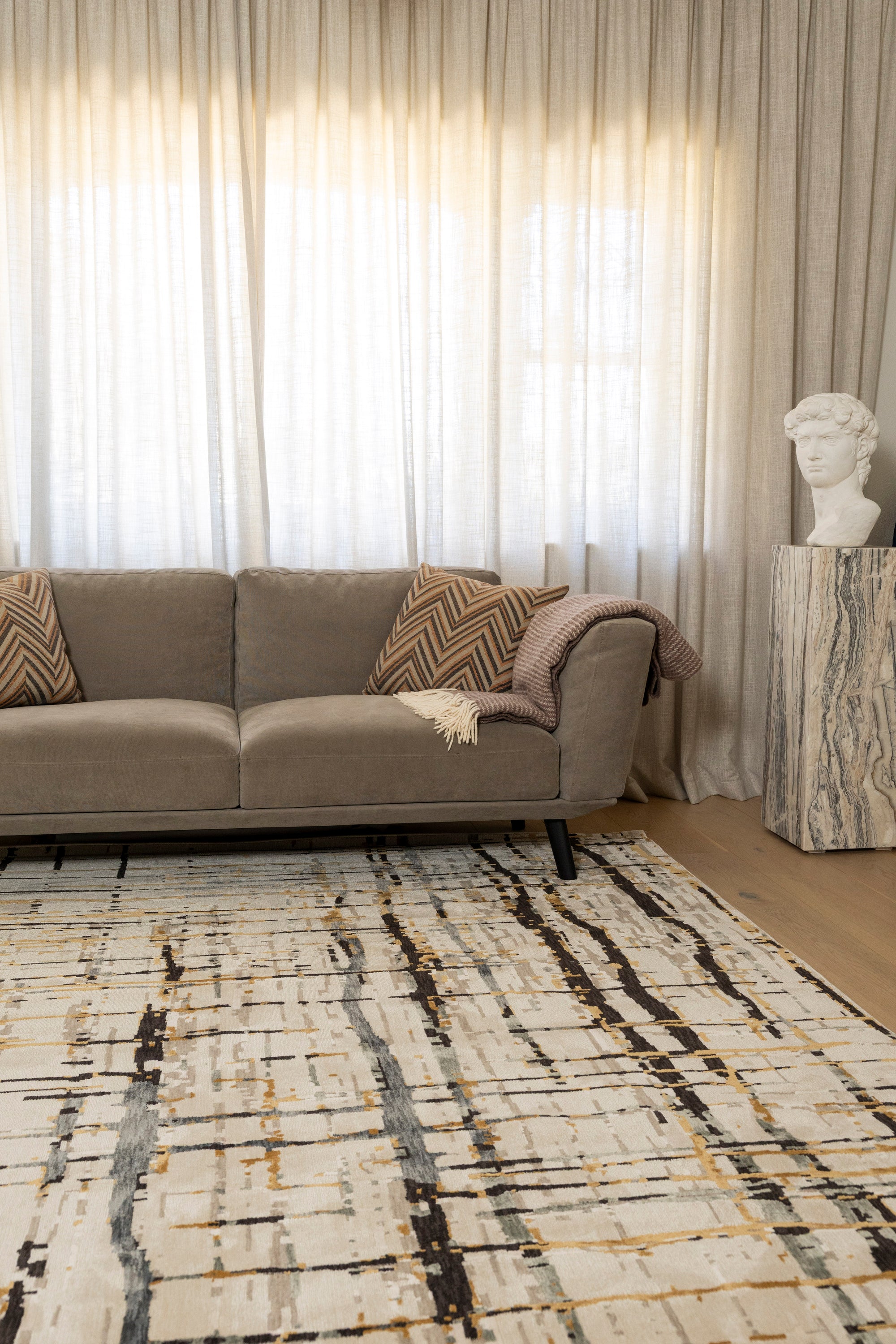 Living room with a grey sofa, Moonlit Bloom Abstract Rug by Four Corners Rugs, and decorative elements.