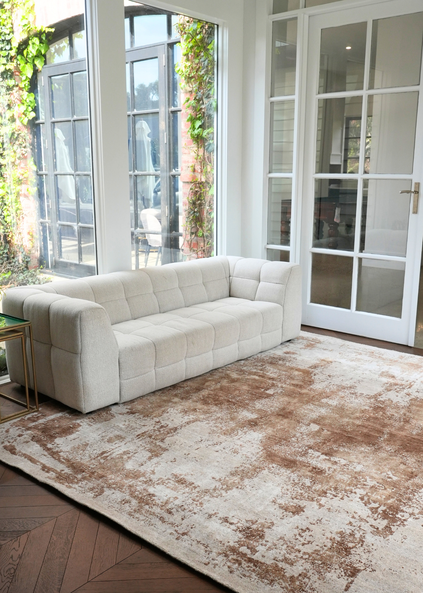 White sofa in a room with large windows and Nude Contrast Gold and Brown Rug By Four Corners Rugs