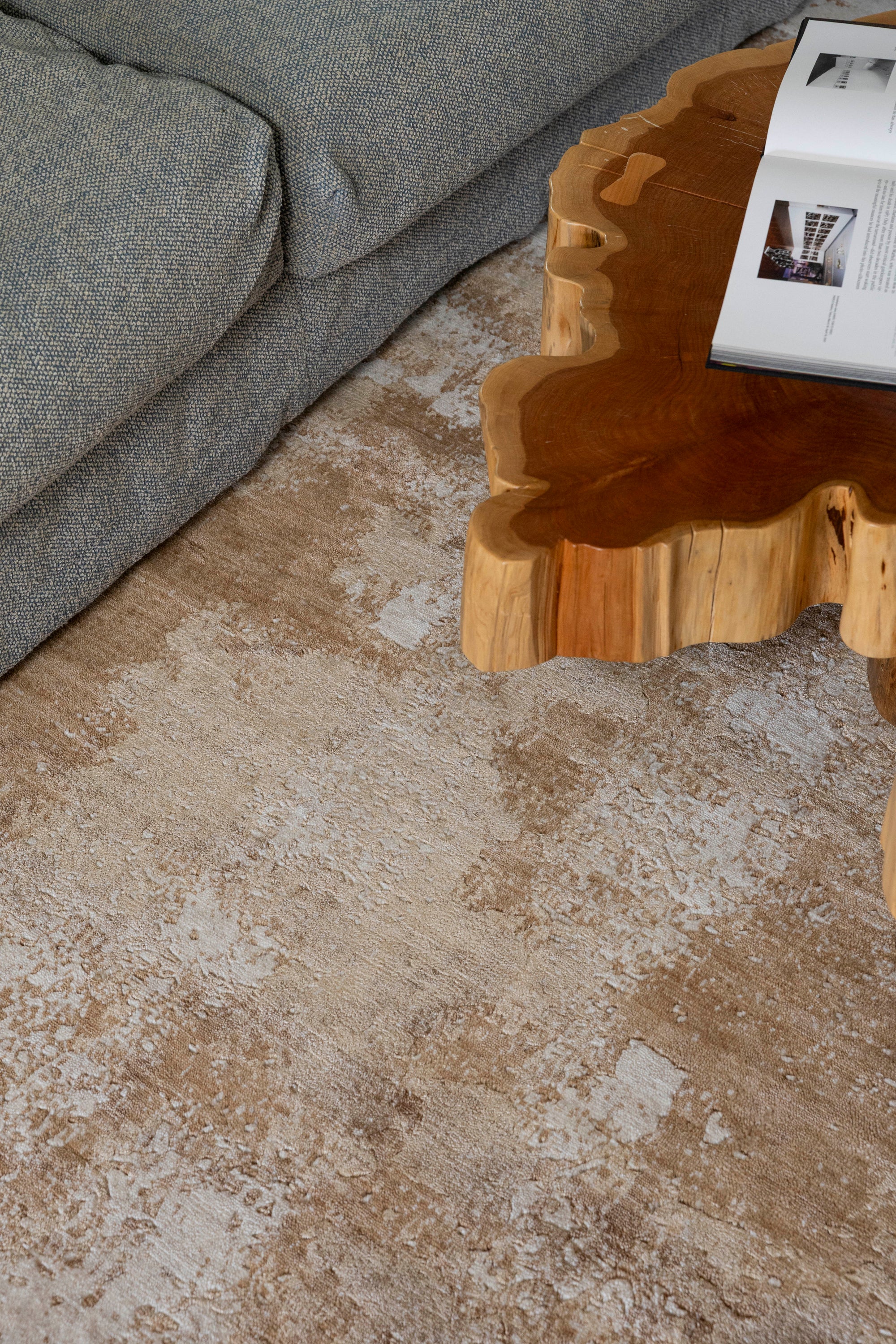 Living room with a wooden coffee table and grey sofa on Nude Contrast Gold and Brown Rug By Four Corners Rugs