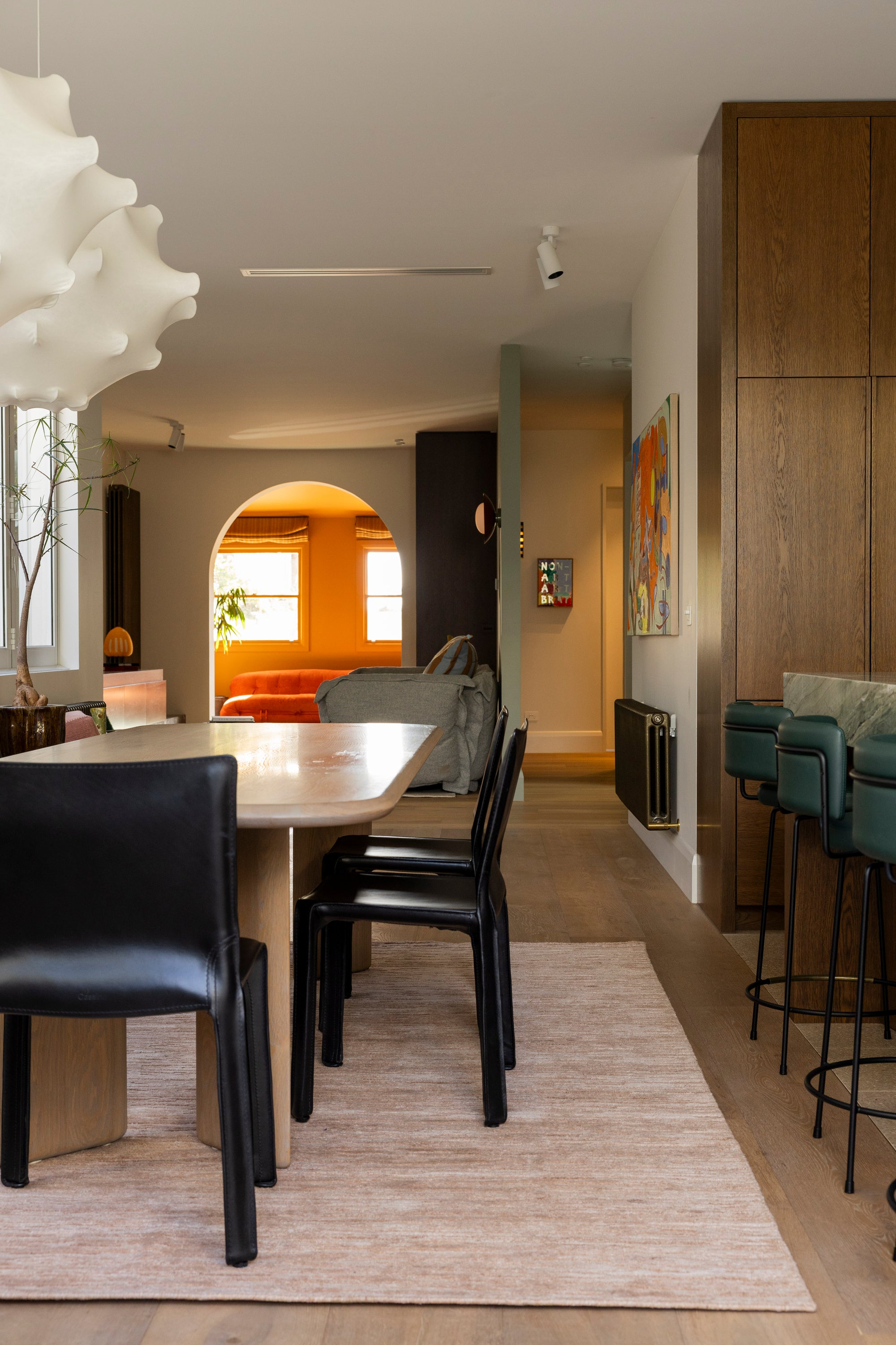 Modern interior with a dining table and chairs, and a bar area on Oceana Dusty Rose by Four Corners Rugs