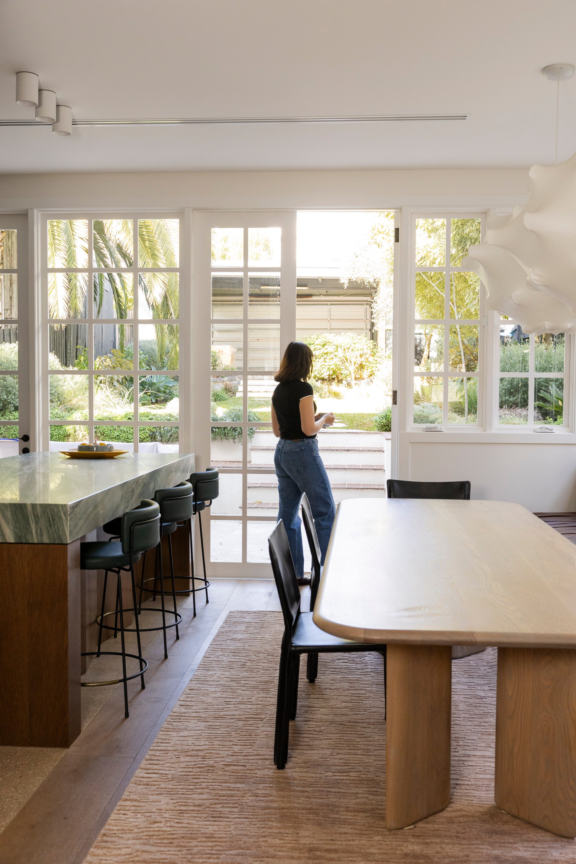 Modern kitchen with large windows, dining table, and island on Oceana Dusty Rose by Four Corners Rugs