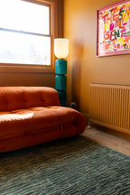 Living room with orange sofa, blue lamp, and colourful wall art on Oceana Forrest Green by Four Corners Rugs