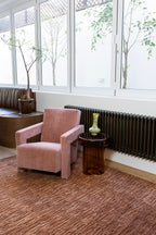 Pink armchair in a room with large windows and Oceana Rust by Four Corners Rugs