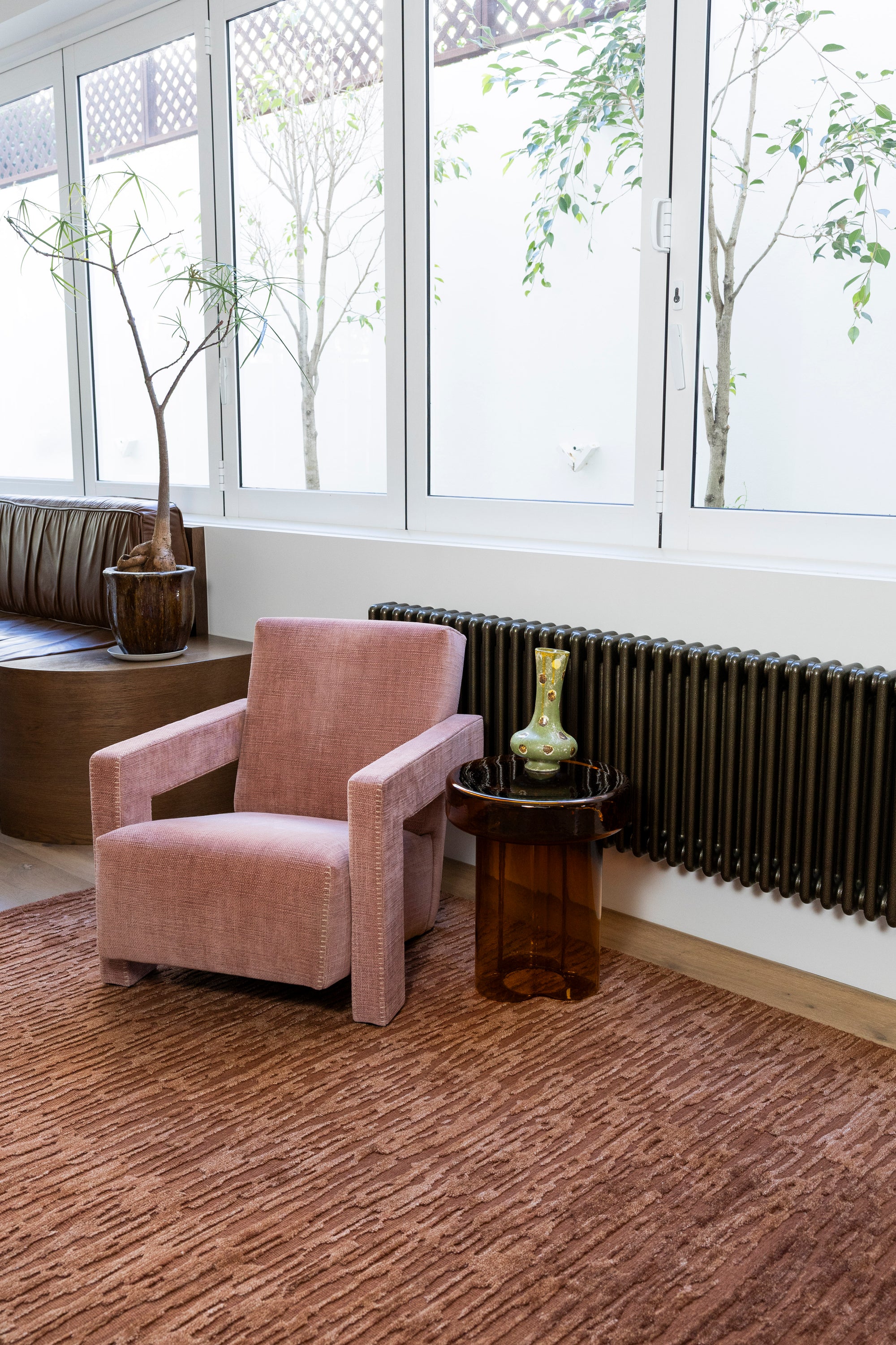 Pink armchair in a room with large windows and Oceana Rust by Four Corners Rugs