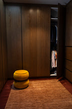 Closet with wooden panels and a yellow ottoman on Oceana Rust by Four Corners Rugs 