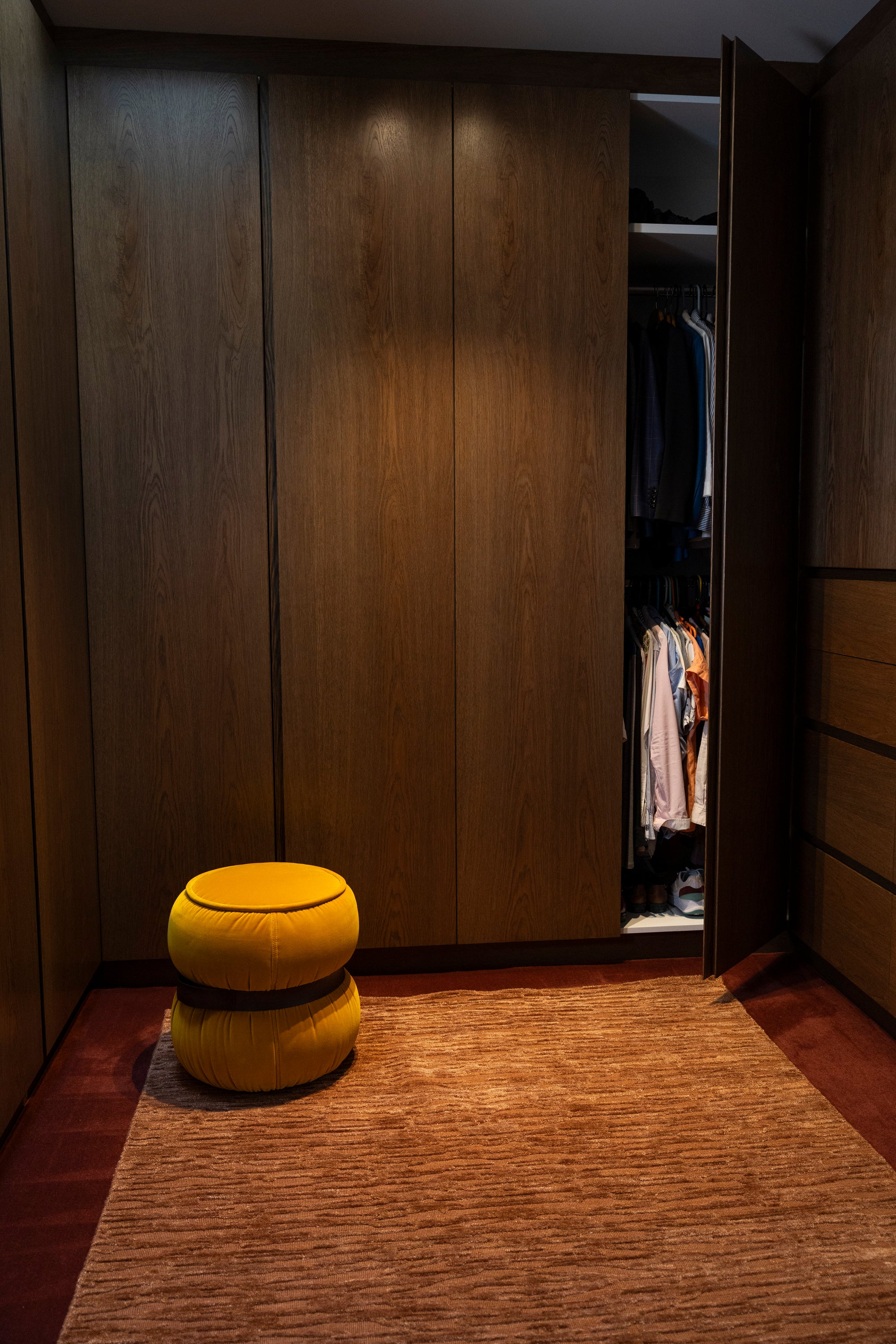 Closet with wooden panels and a yellow ottoman on Oceana Rust by Four Corners Rugs 