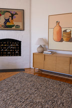 Living room with wooden sideboard, Pebbles Brown and Black by Four Corners Rugs, and wall art