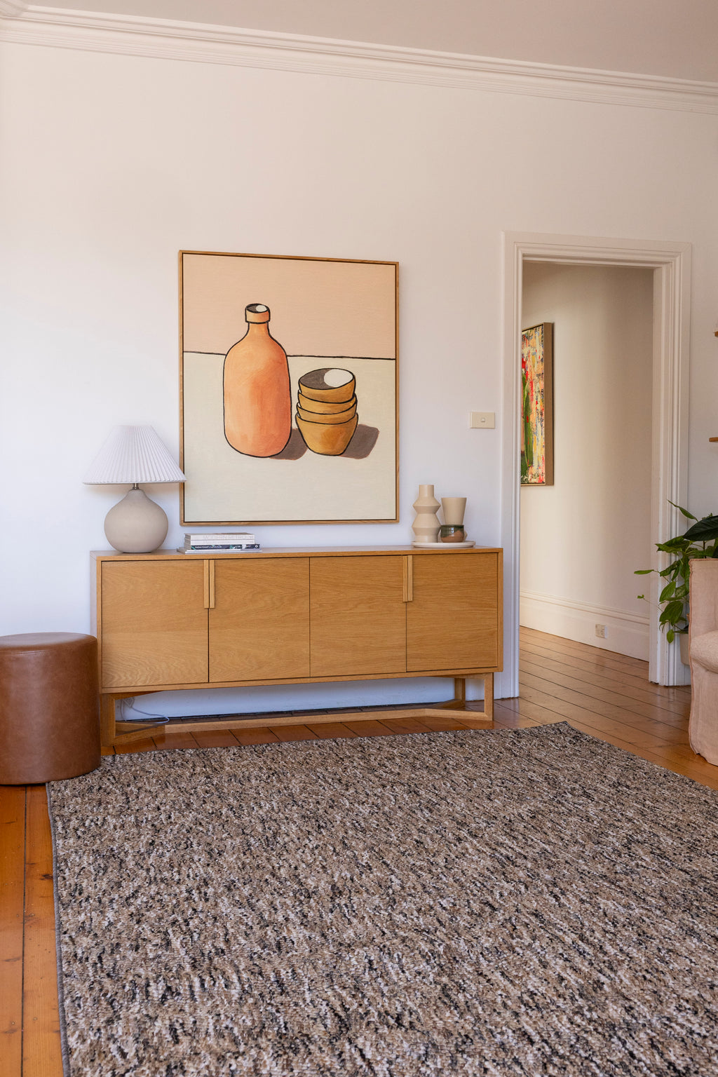 Living room with wooden sideboard, Pebbles Brown and Black by Four Corners Rugs, and wall art