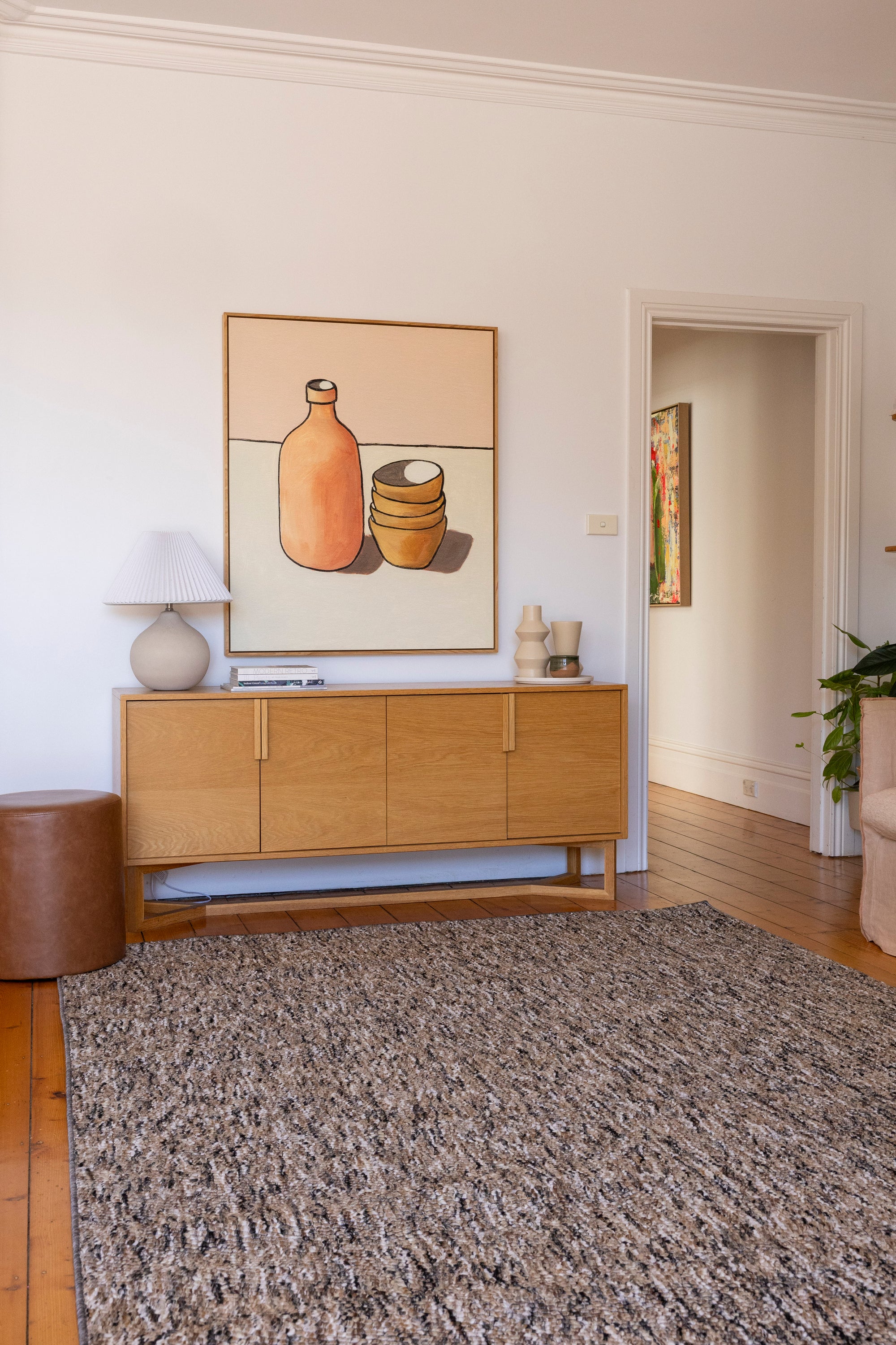 Living room with wooden sideboard, Pebbles Brown and Black by Four Corners Rugs, and wall art