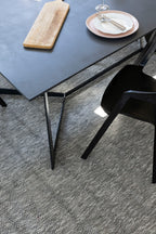 Modern black dining table with a chair on Pebbles Light Grey by Four Corners Rugs