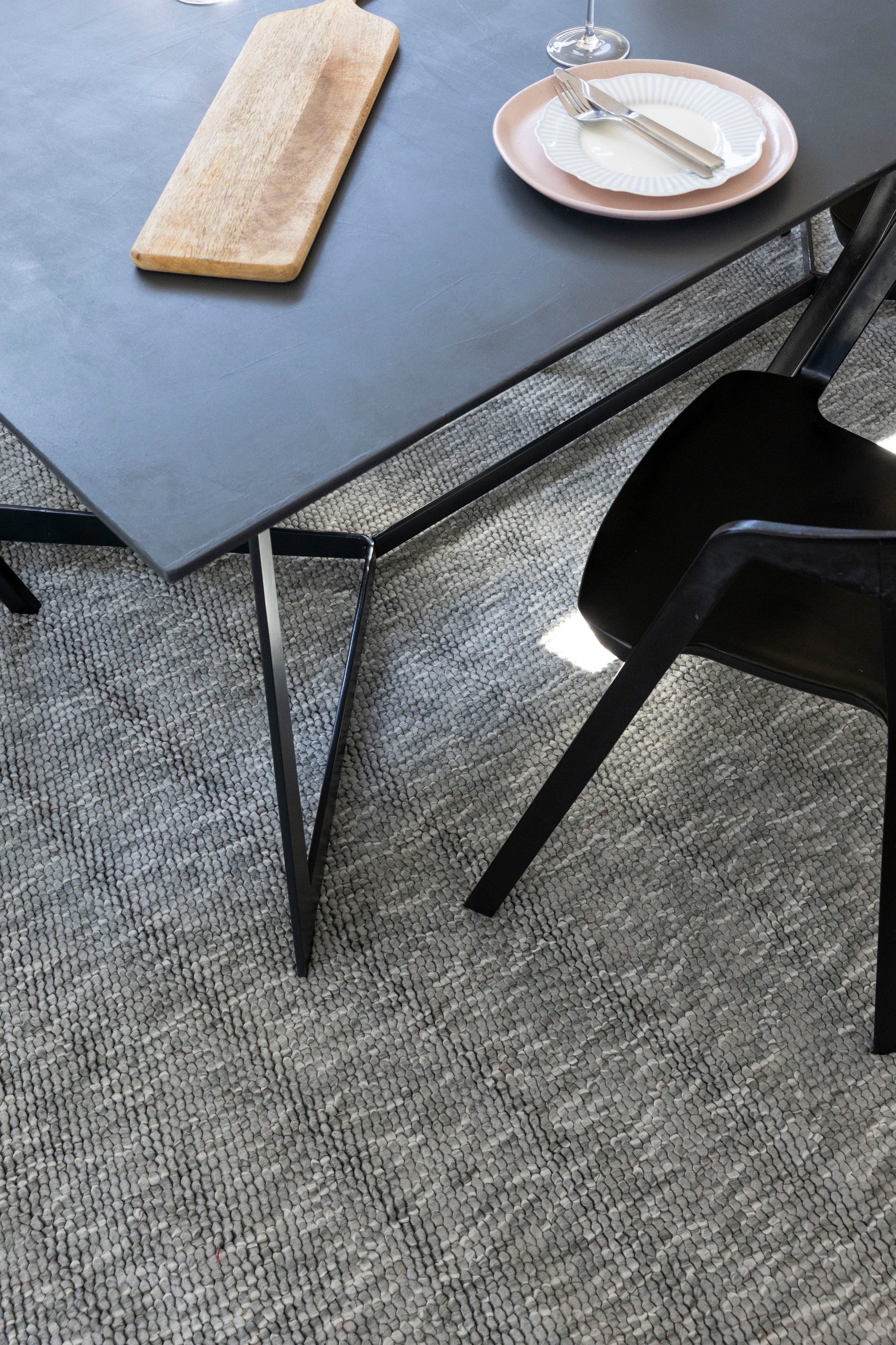 Modern black dining table with a chair on Pebbles Light Grey by Four Corners Rugs