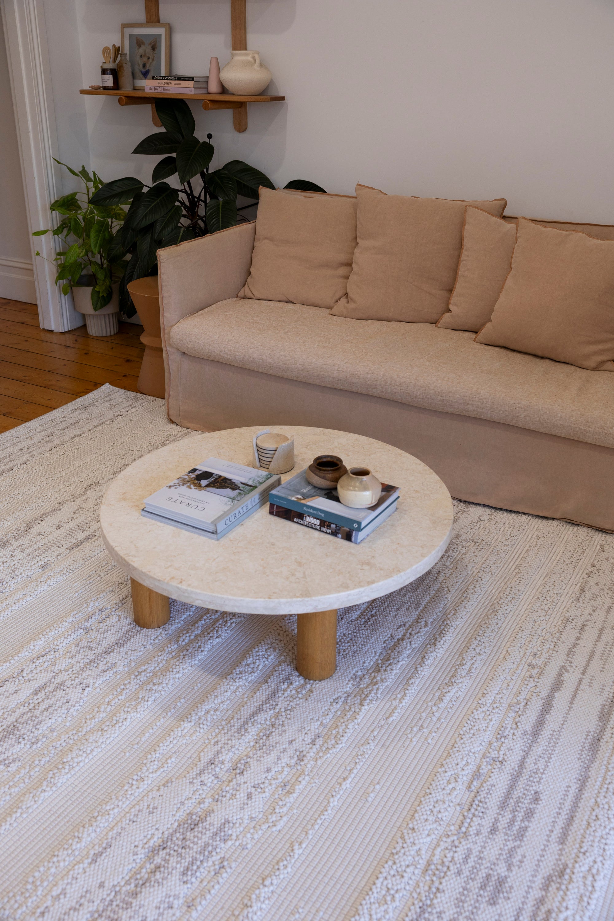 Round coffee table with books and decor items in a living room setting on Pebbles White Rug by Four Corners Rugs