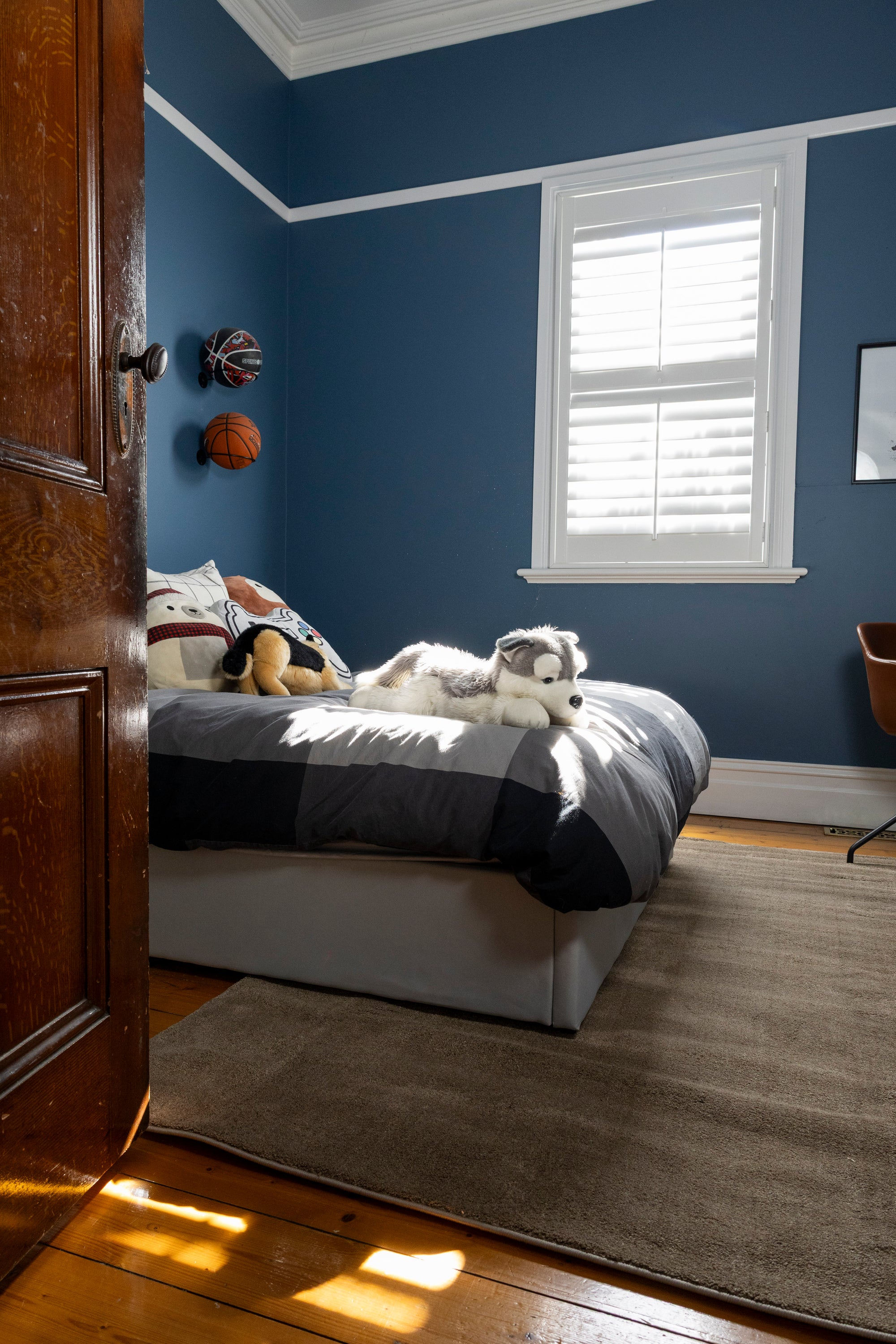 Bedroom with blue walls, a bed with stuffed animals and Plush Brown Rug by Four Corners Rugs