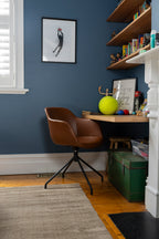 Bedroom office with a brown chair, desk, and shelves against a blue wall and Plush Brown Rug by Four Corners Rugs