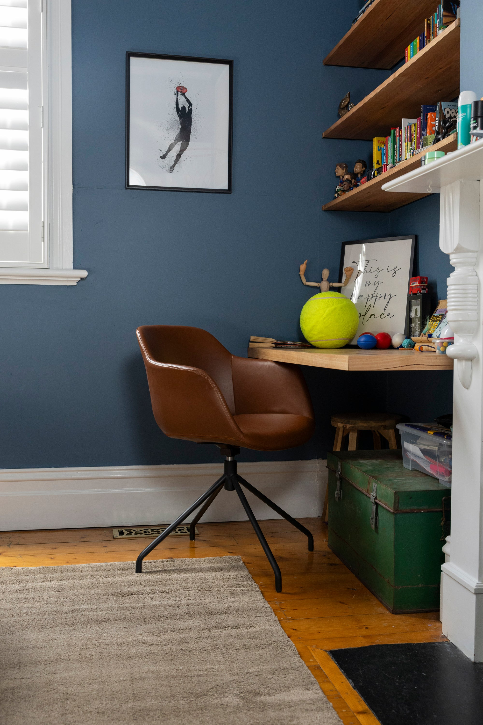 Bedroom office with a brown chair, desk, and shelves against a blue wall and Plush Brown Rug by Four Corners Rugs