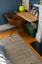 Small home office with a wooden desk, brown chair and Plush Brown Rug by Four Corners Rugs