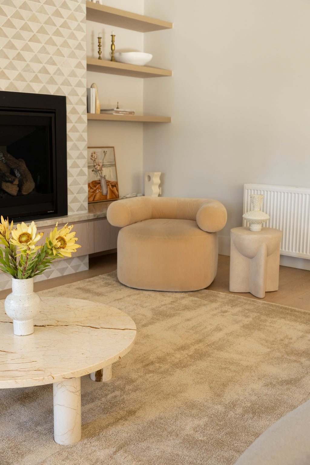 Modern living room with beige armchair, round coffee table, and decorative elements on Plush Gold Rug by Four Corners Rugs