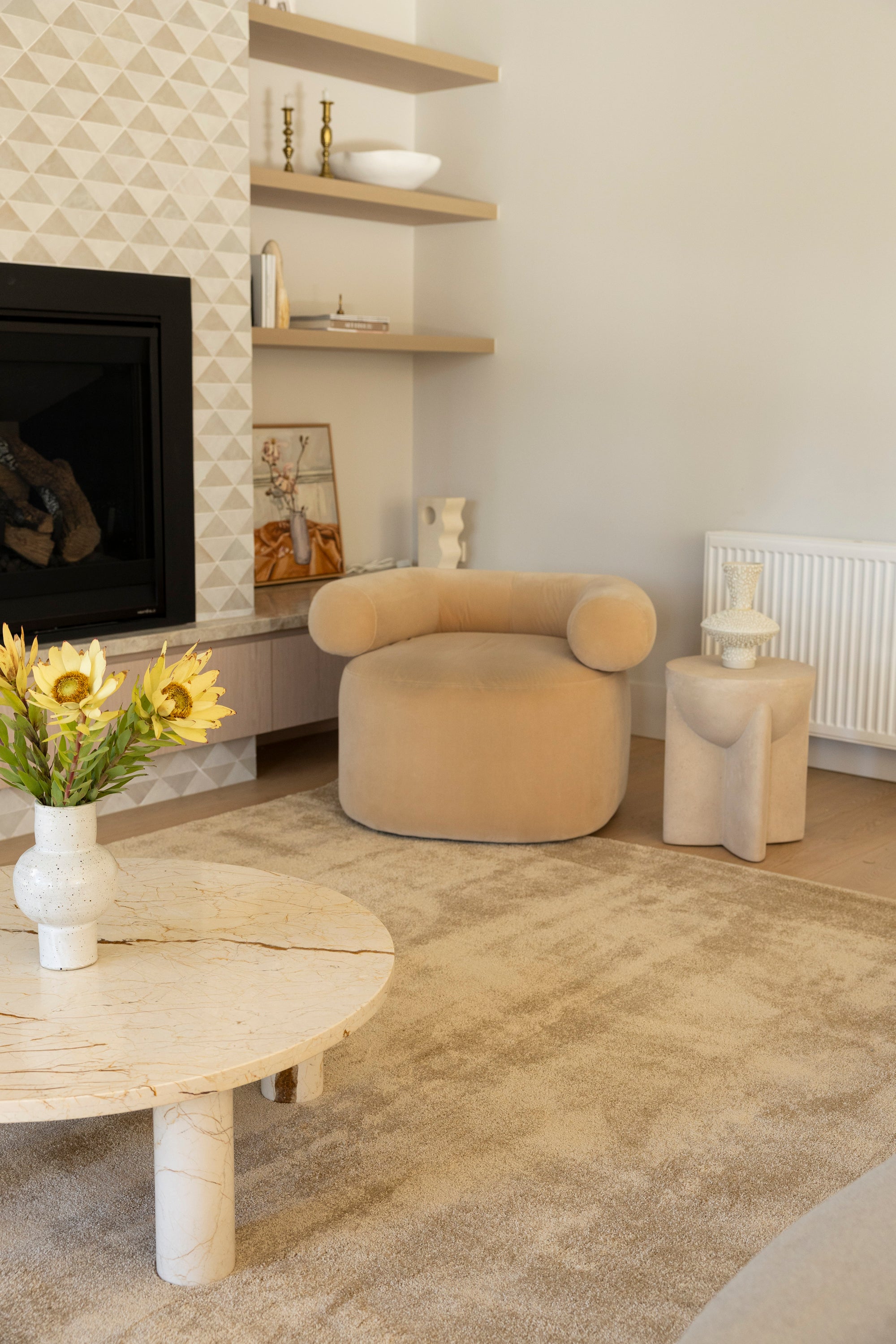 Modern living room with beige armchair, round coffee table, and decorative elements on Plush Gold Rug by Four Corners Rugs