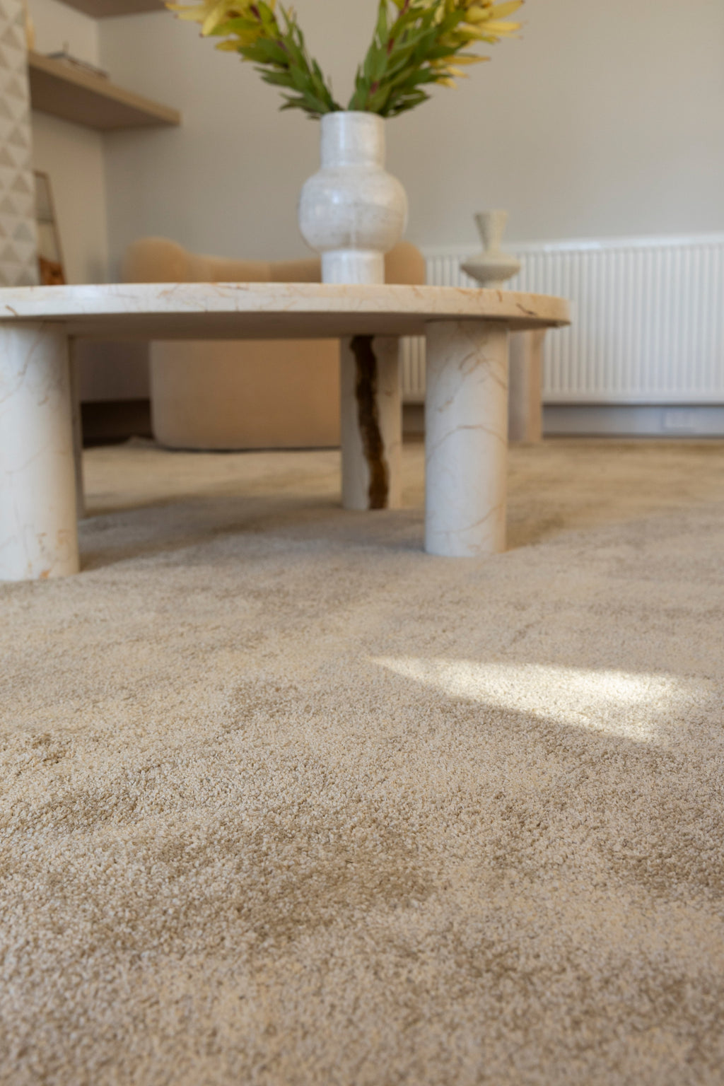 Plush Gold Rug by Four Corners Rugs with a marble coffee table and vase in the background