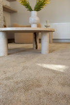 Plush Gold Rug by Four Corners Rugs with a marble coffee table and vase in the background