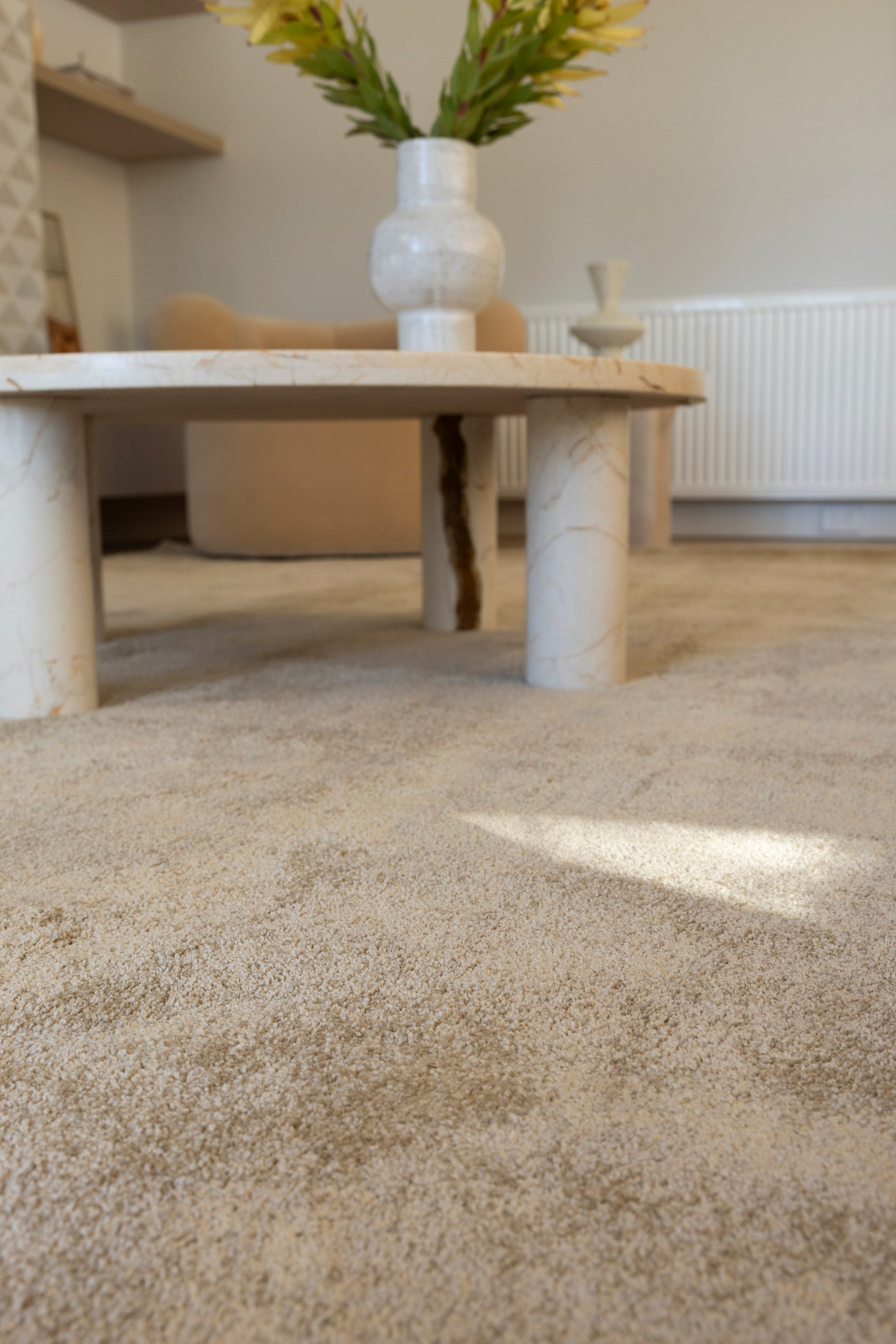 Plush Gold Rug by Four Corners Rugs with a marble coffee table and vase in the background