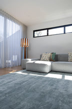 Modern living room with a grey sectional sofa, patterned cushions, a striped lamp and Plush Ice Blue Rug by Four Corners Rugs