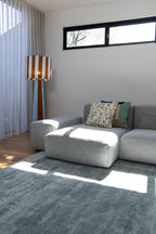 Modern living room with a grey sofa, patterned cushions, a striped floor lamp and Plush Ice Blue Rug by Four Corners Rugs
